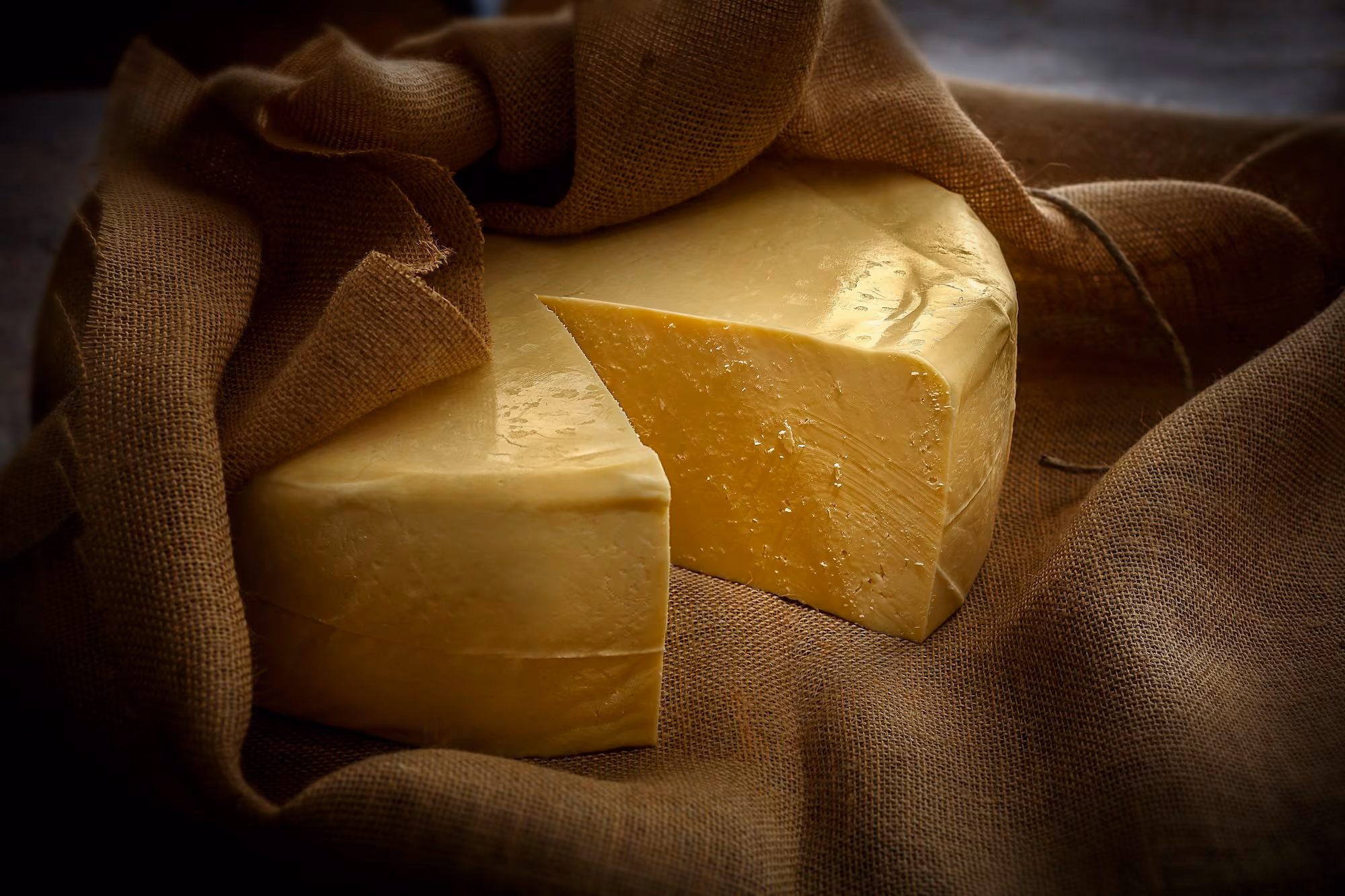 A wheel of Queso Fresco cheese wrapped in brown linen.