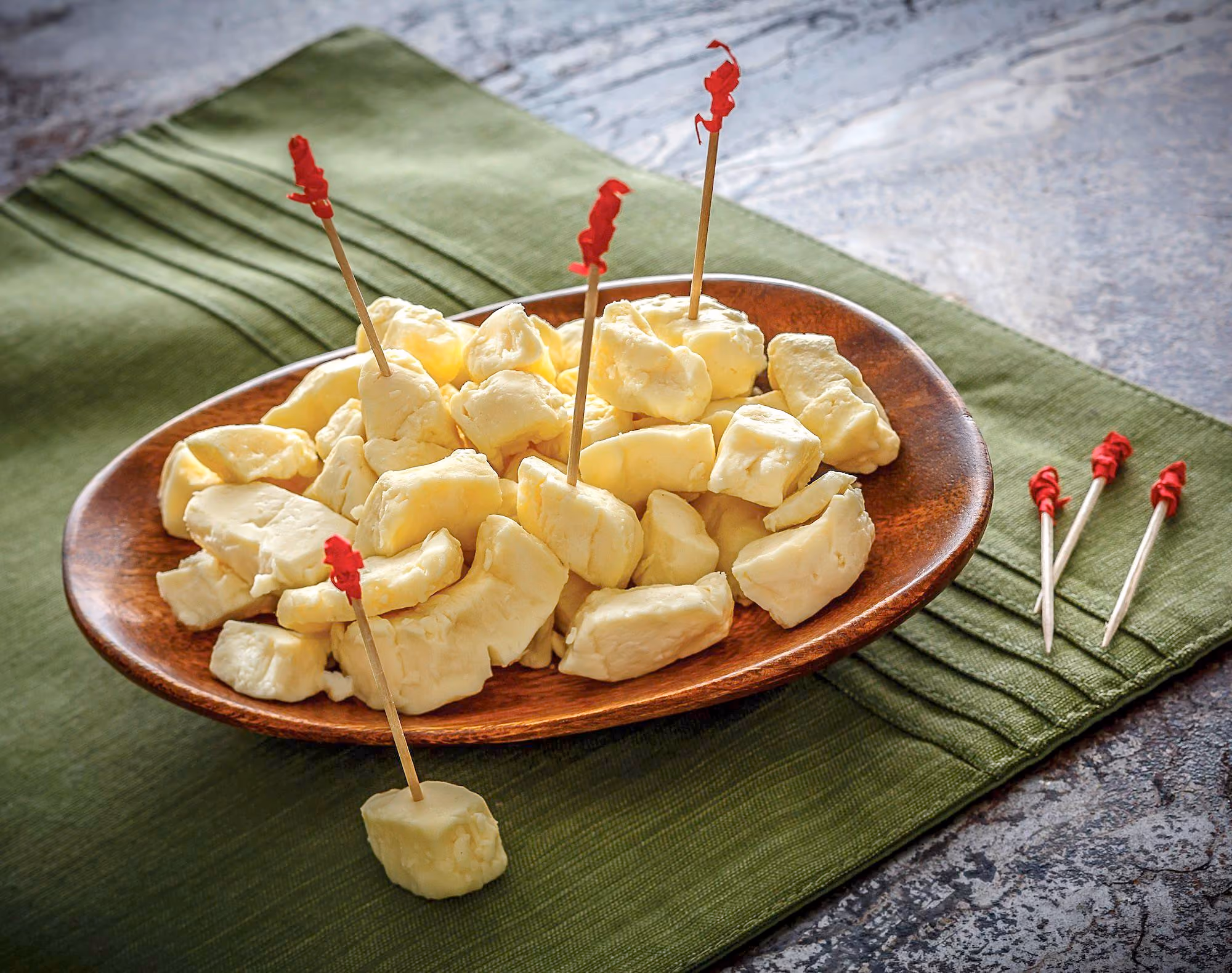 A wooden plate filled with white cheese curds.