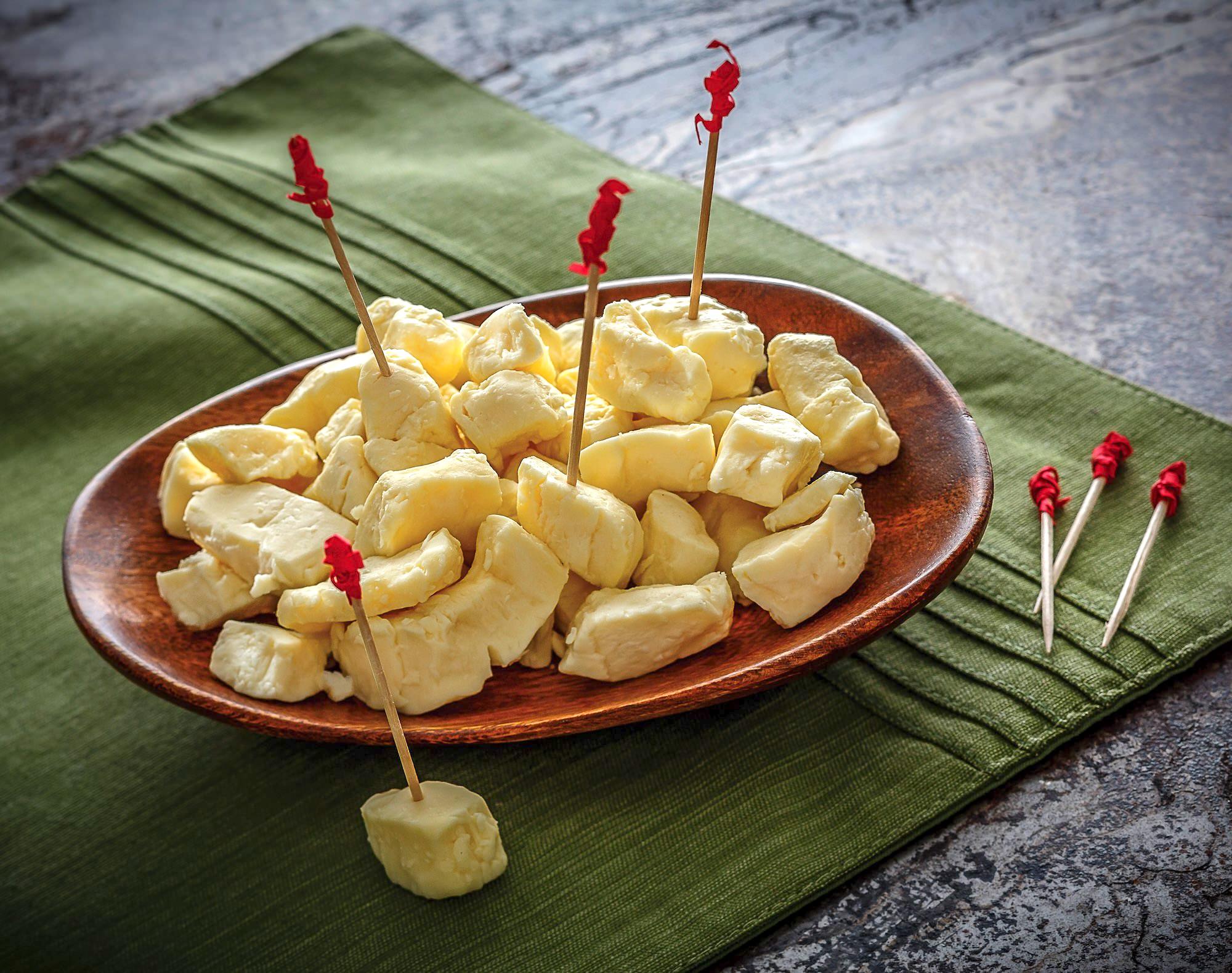 A wooden plate filled with white cheese curds. 