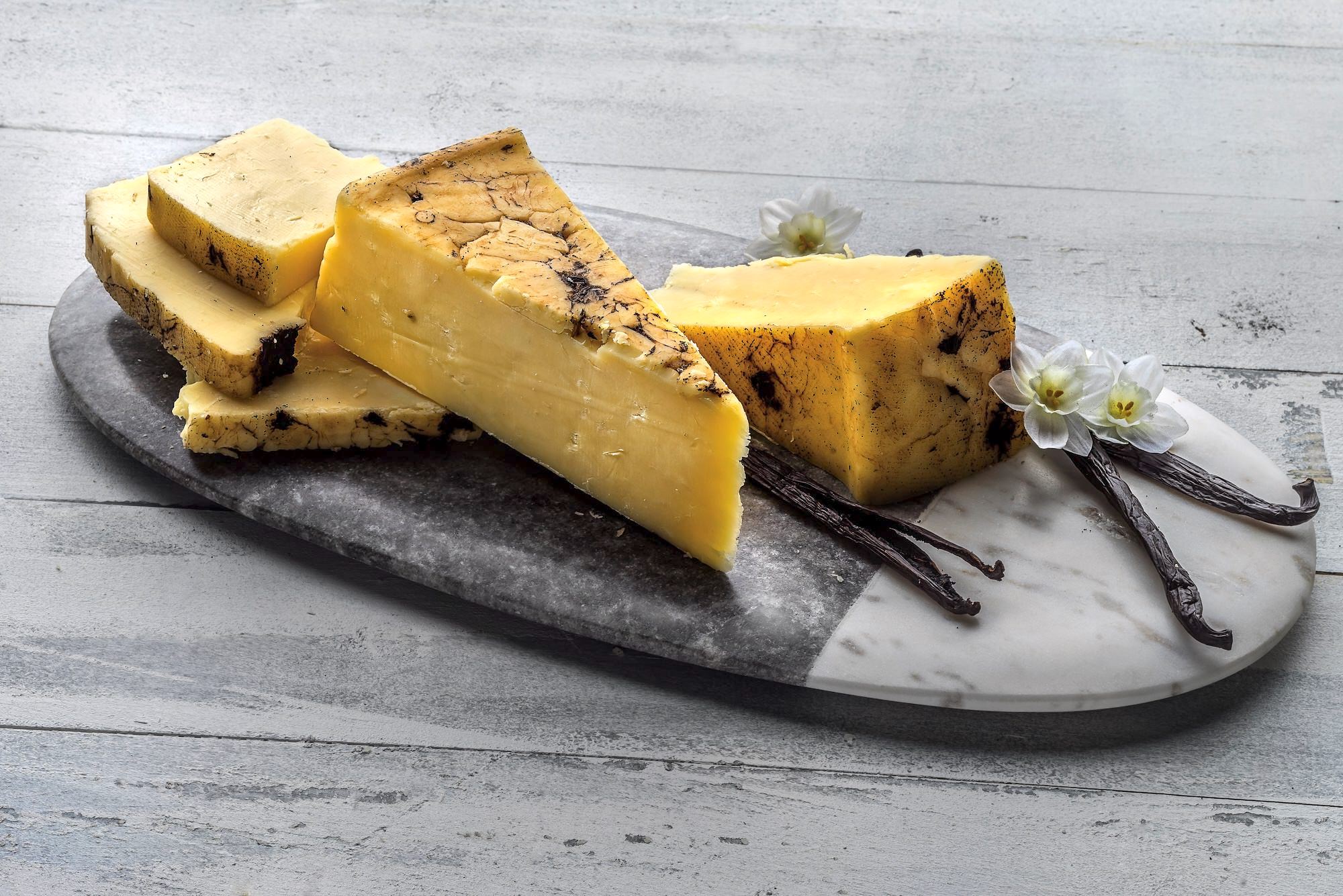 Fresh cheddar rubbed with tahitian vanilla bean on a stone cutting board.