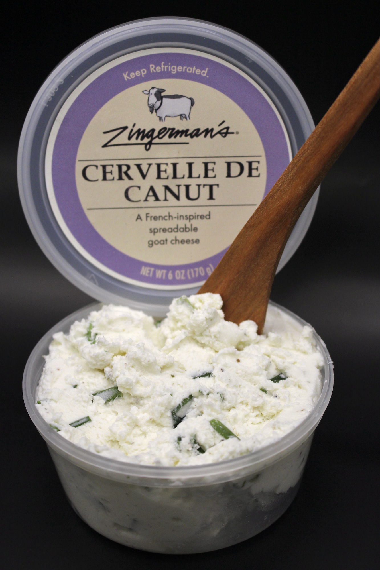 photo of a clear container with a white cheese spread, a wooden spreader sticking out of the cheese, and the container lid propped up and reads "Zingerman's Cervelle de Canut"