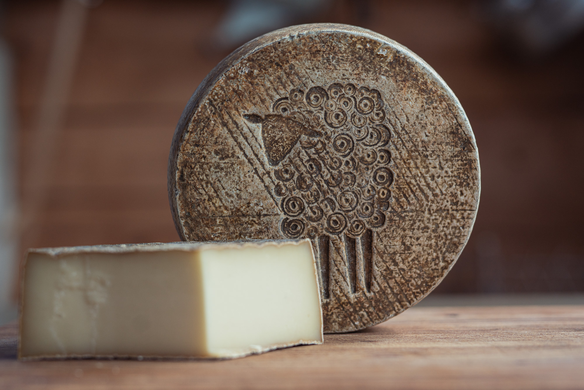 A wheel and a wedge of Green Dirt Farm's Prairie Tomme sheep milk cheese