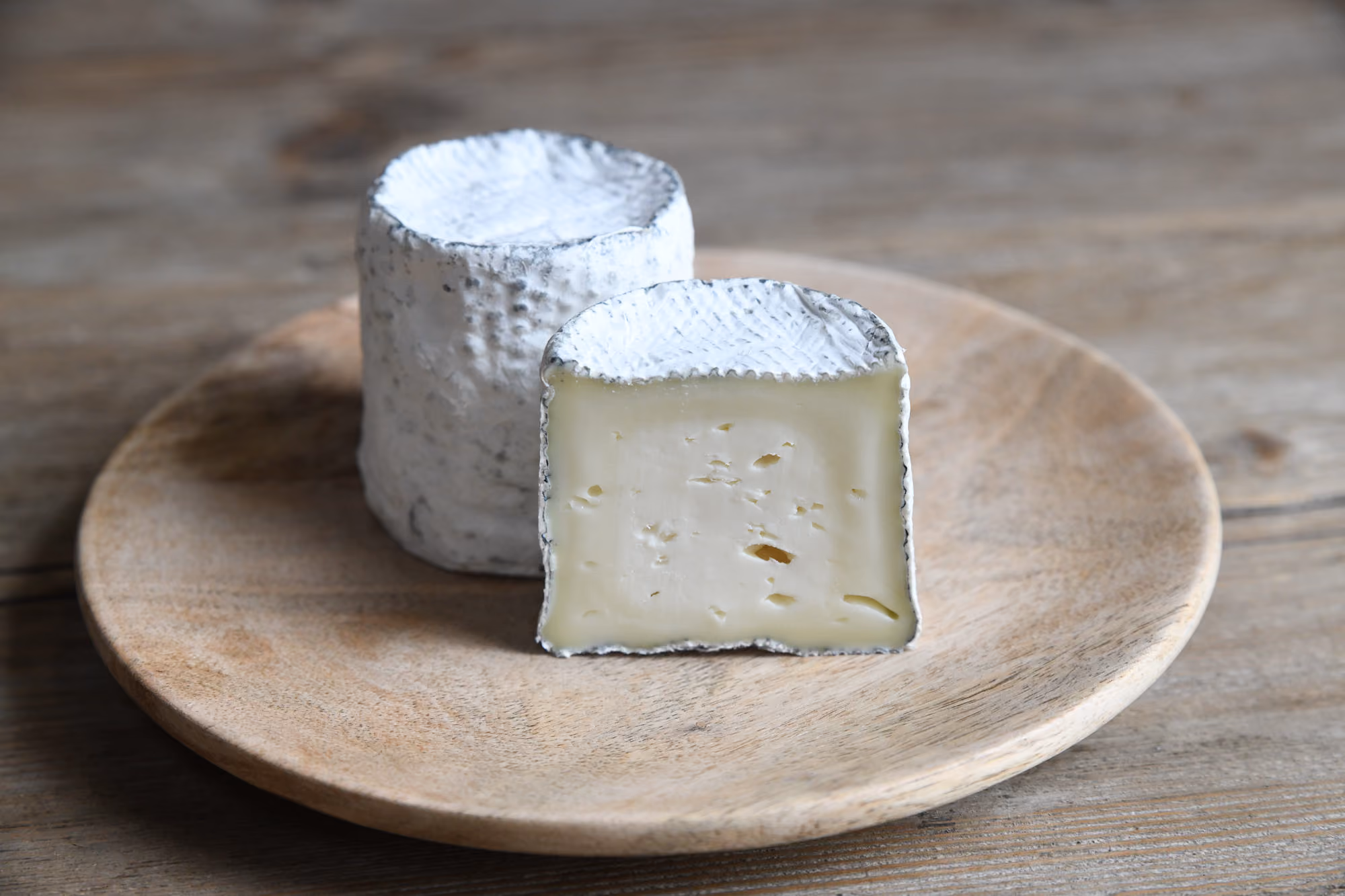 This is an image of Green Dirt Farm's Dirt Lover cheese, pictured whole and cut in half.