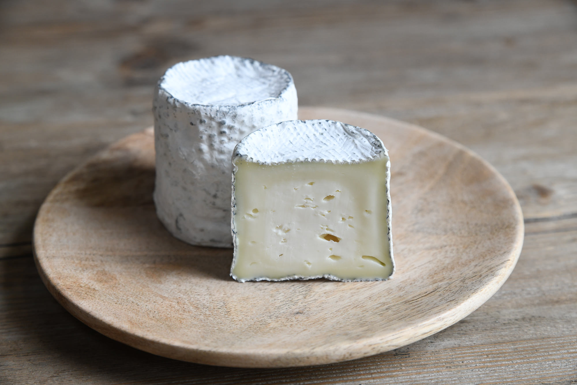 This is an image of Green Dirt Farm's Dirt Lover cheese, pictured whole and cut in half.
