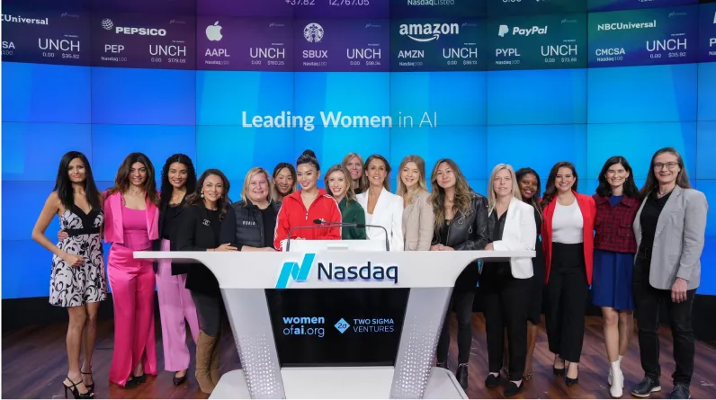 Group of diverse women standing behind a Nasdaq podium with a screen behind displaying 'Leading Women in AI' and stock market ticker symbols.