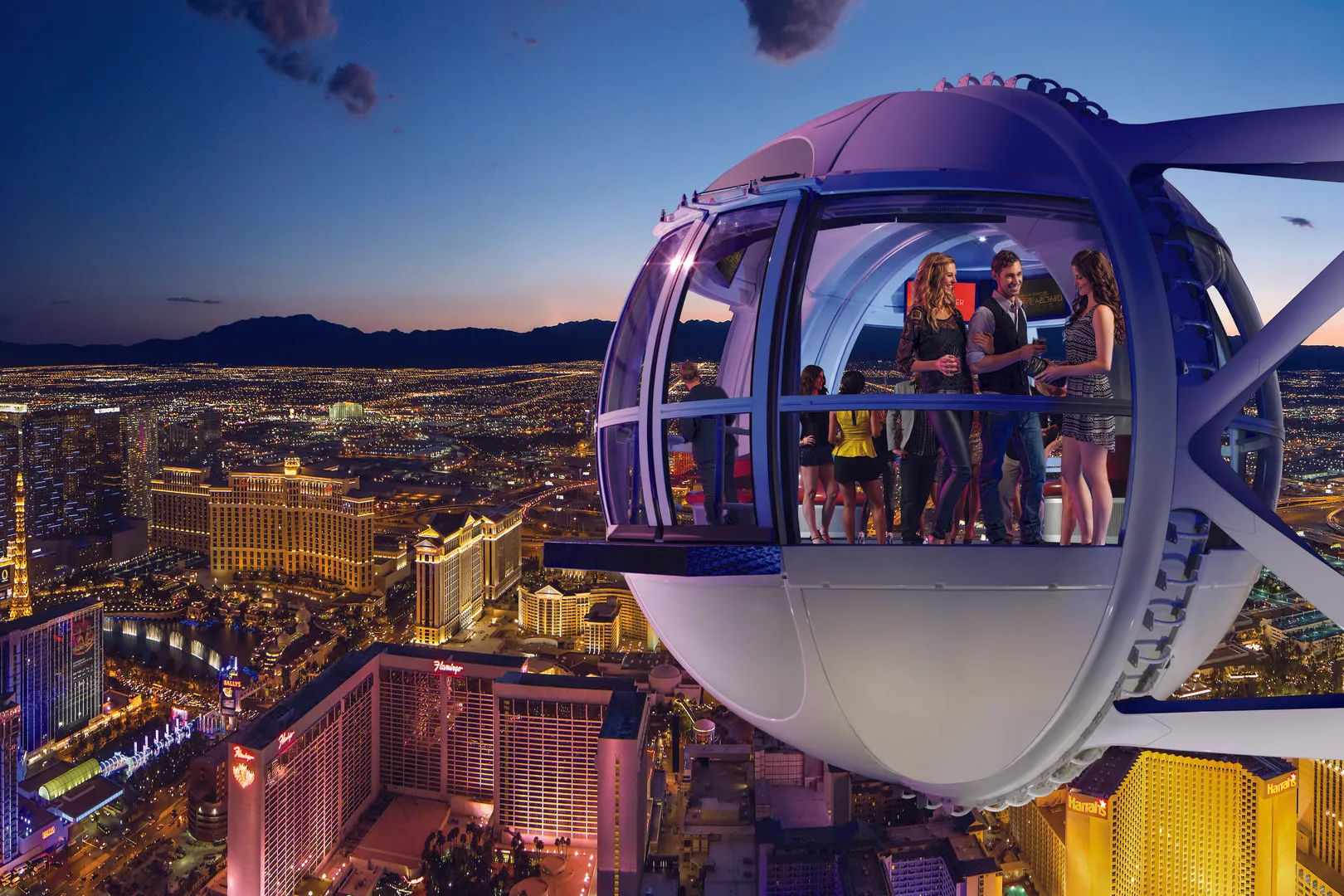 People socializing inside a lit-up observation cabin of a large Ferris wheel overlooking a cityscape at dusk.