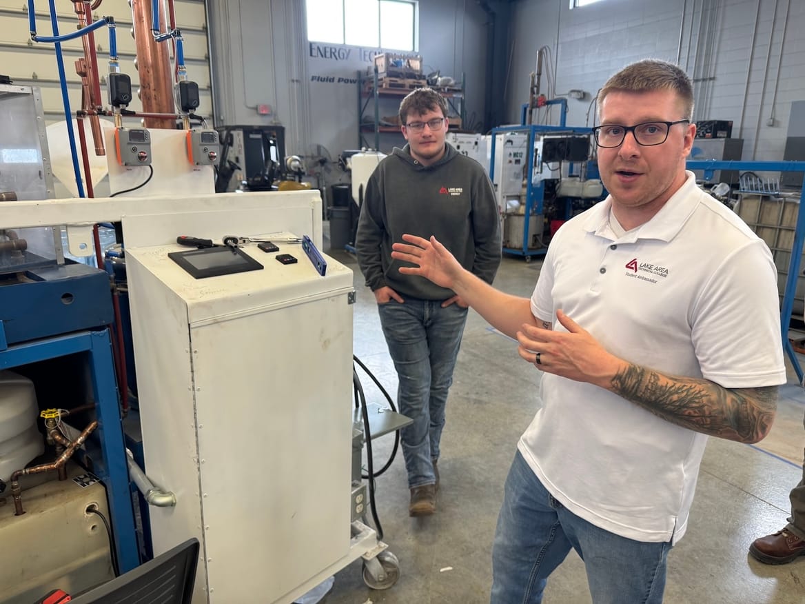Two people stand next to machinery