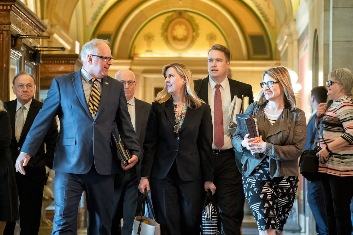 A group of people in business clothes walk through a government building