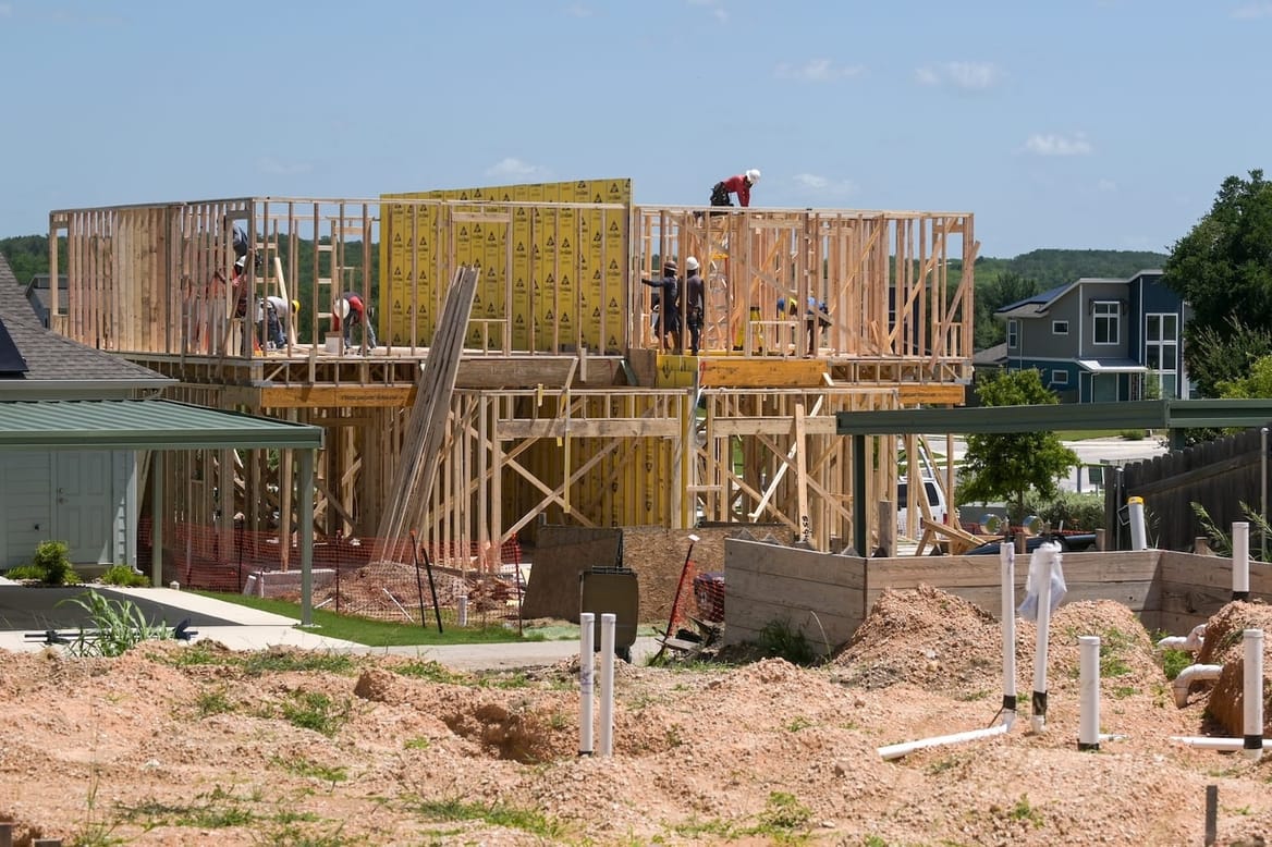 Workers on a construction site with wooden framing for a house