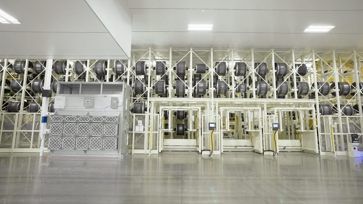 Interior of a factory, with large piping and equipment lined up on a wall