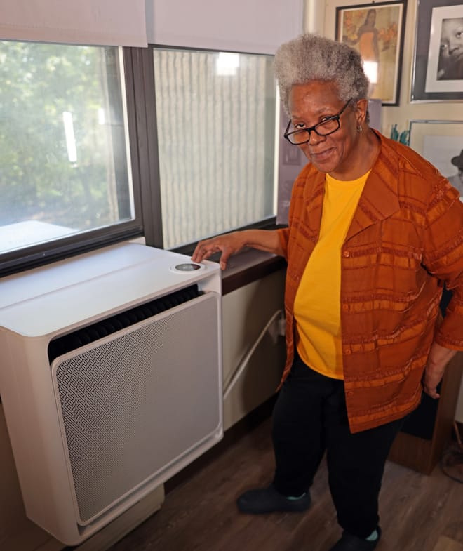 A person stands next to HVAC equipment installed in a window