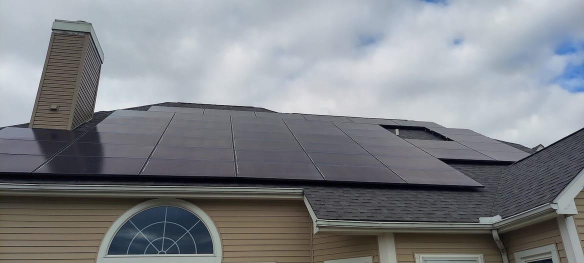 Rooftop solar panels on a home against a cloudy sky