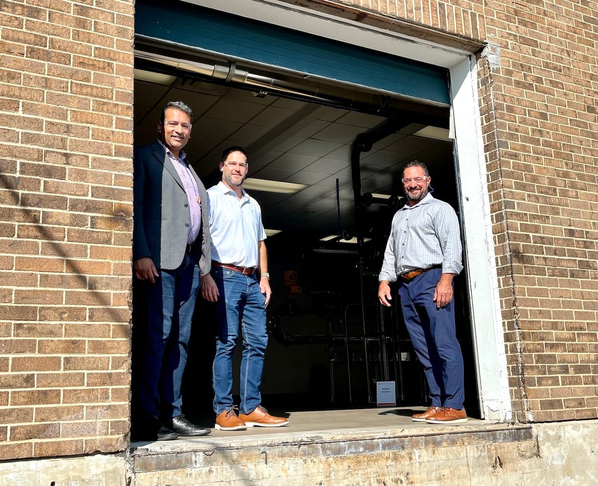A group of people stand in the doorway of a warehouse