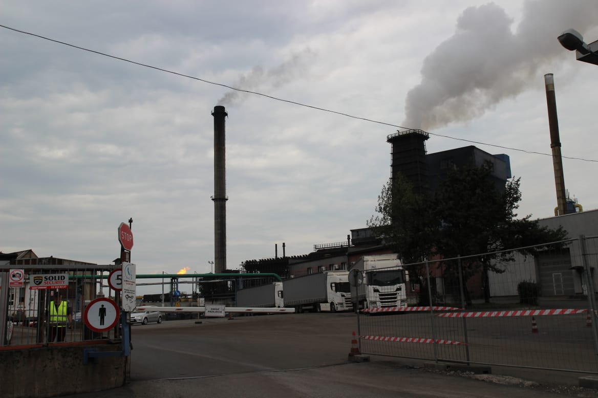 Bytom coking plant shooting smoke and steam across an asphalt street under a drab, gray sky