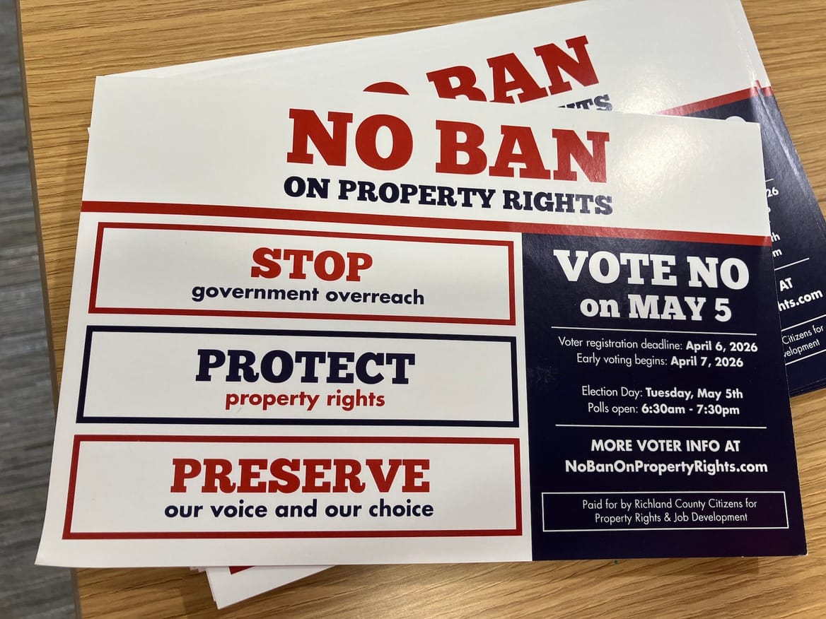 Close-up of a stack of flyers reading "No Ban on Property Rights. Vote no on May 5" in a white, red, and blue design