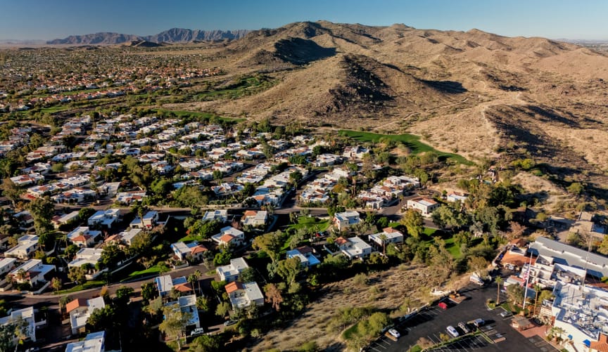 Aerial view of a residential neighborhood nestled below rolling brown mountains