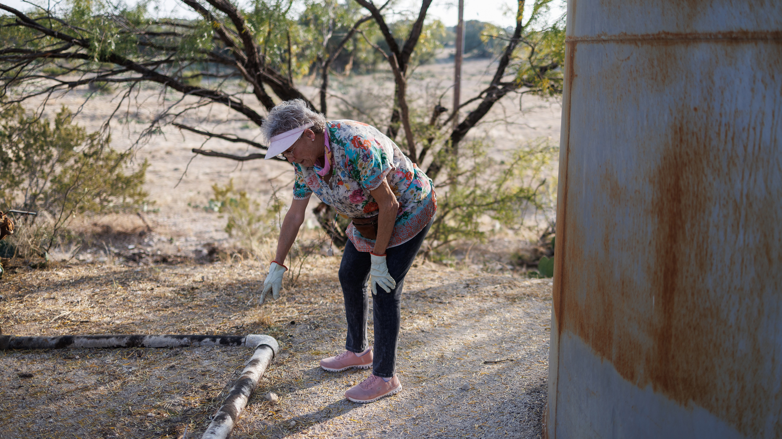 Jackie Chesnutt points to a leaky oil pipe next to a CORE Petro tank battery in disrepair on her property near Knickerbocker, Texas.