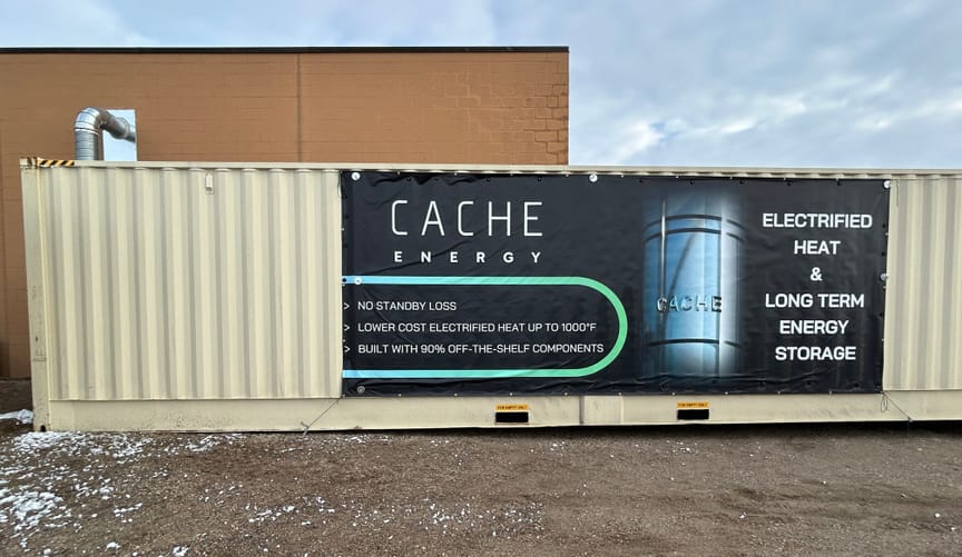 A beige storage container with a sign for Cache Energy, "Electrified Heat and Long Term Energy Storage