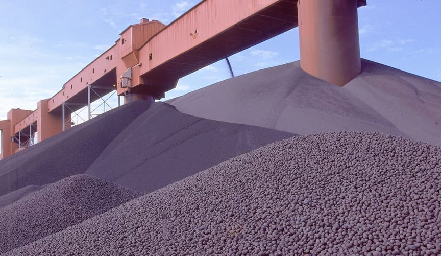 Huge mound of pellets with a terra-cotta corrugated steel structure high above them