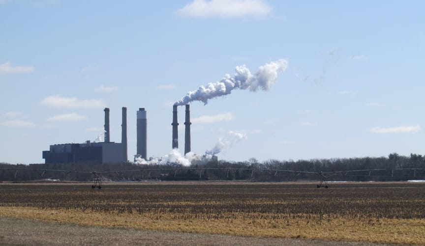 Power plant in the distance with smoke billowing from one or two of four smokestacks