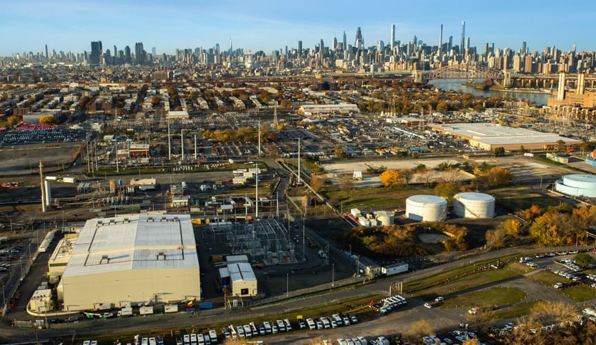 New York City skyline in the distance on a clear day with a light colored converter station on the left