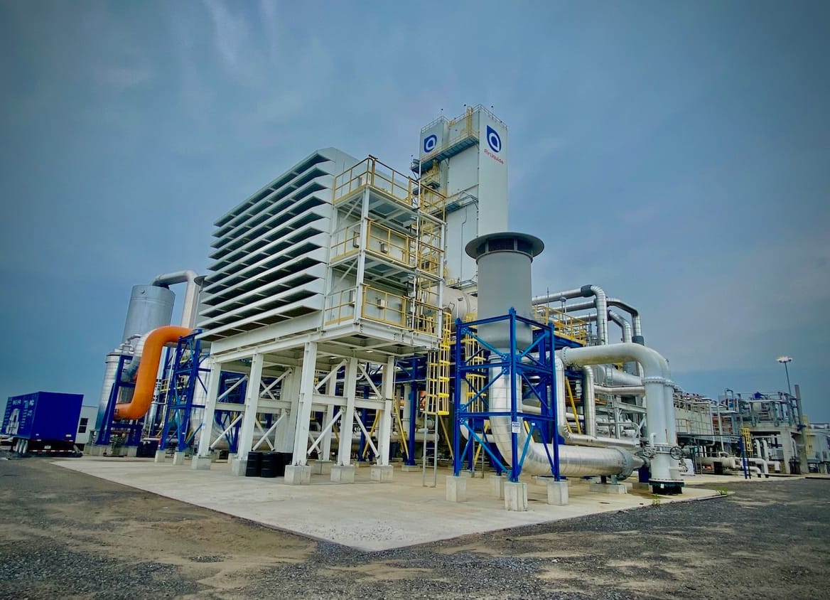 White structure with blue, orange, and white pipes on a concrete base