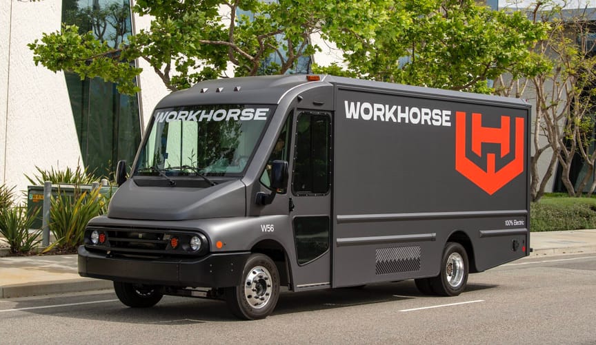 A big, shiny gray van with "Workhorse" on the side driving down a tree-lined street.