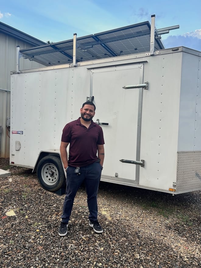 Man standing in front of white trailer with solar panels