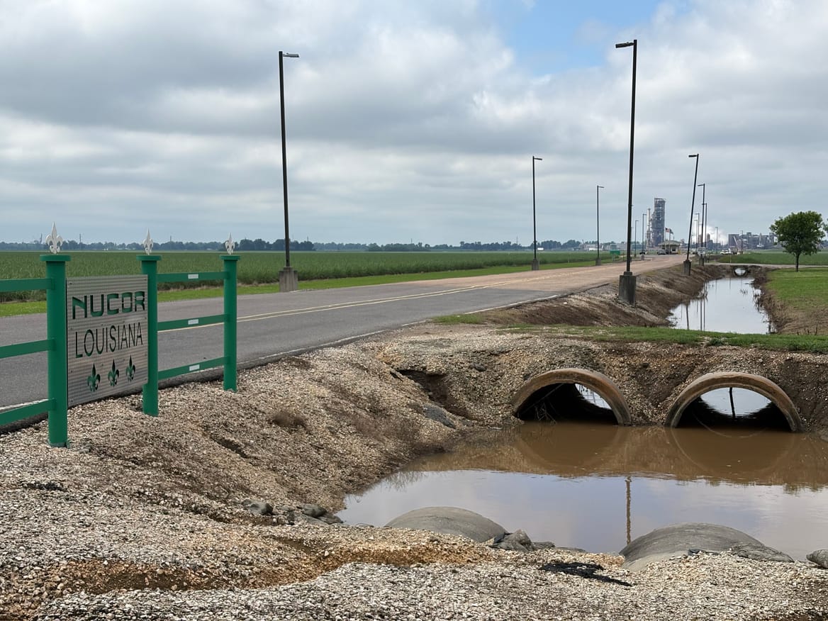Sign with "Nucor Louisiana" between a roadway and drainage ditch