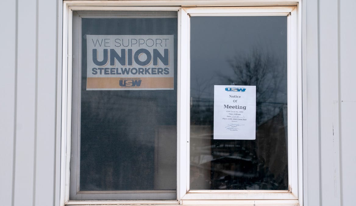 Window with "We support union steelworkers" sign and another paper with meeting notice