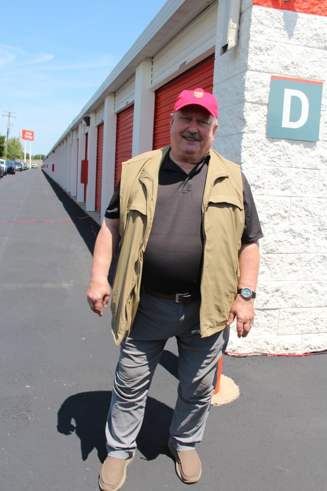 Man smiling standing next to a Public Storage building with orange doors