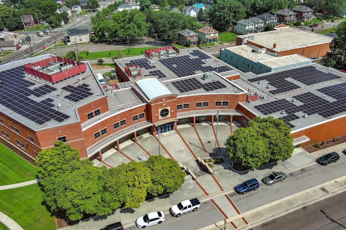 Overhead shot of red schook building with curved central portion, solar panels on roof