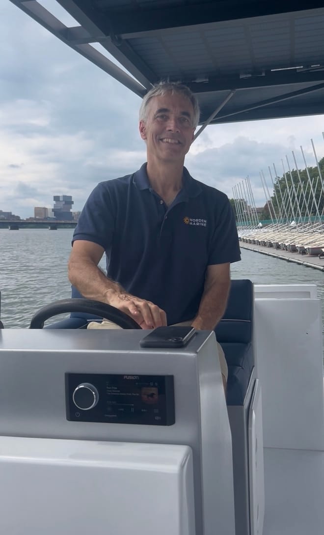 Man in blue short-sleeve shirt with Worden Marine logo pilots a boat