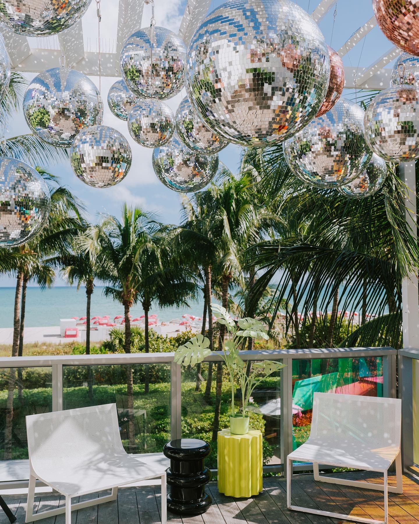 A creative image from an art exhibit with disco balls and palm trees.  Its a beautiful day
