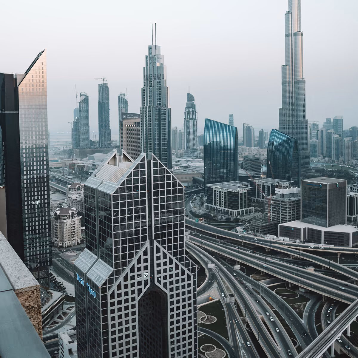 A city skyline with a tall building and a highway.