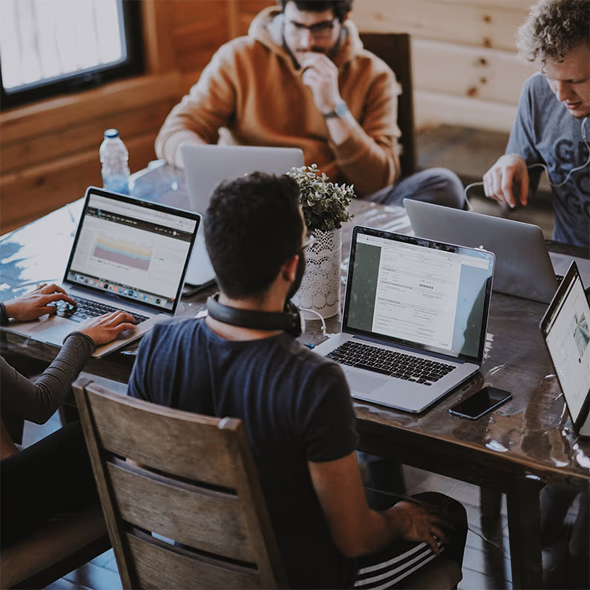 A group of people sitting around a table with laptops.