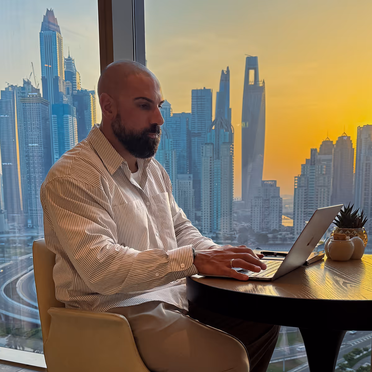 A man in a white shirt is using a laptop.
