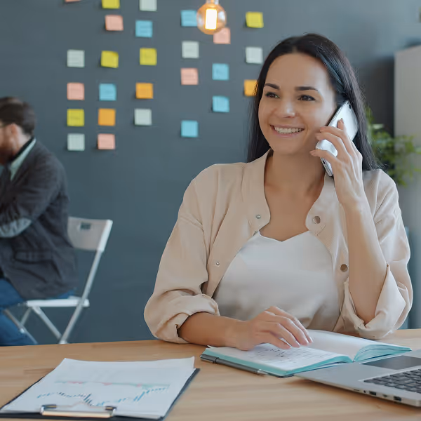 A woman talking on a cell phone while sitting at a desk.