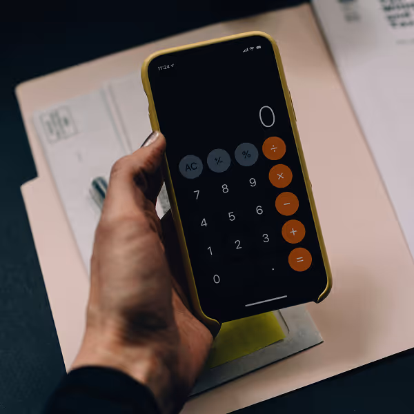 A person holding a calculator with the number 0 on the screen.