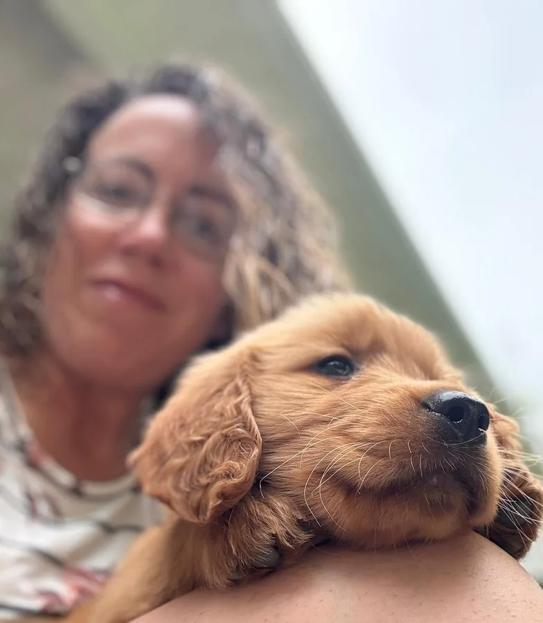 A woman cuddling a Golden Retriever puppy