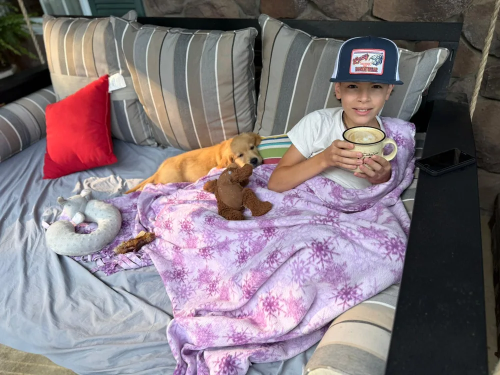 A boy and a Golden Retriever puppy relaxing on a couch