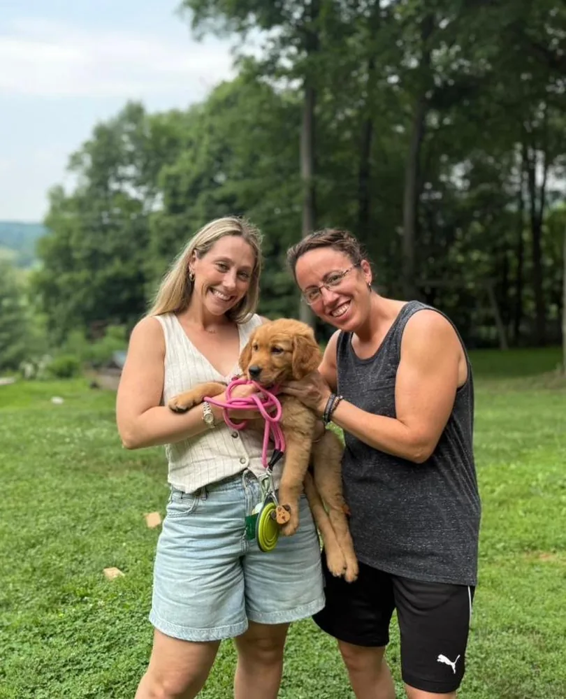 Lillian (right) with a Golden Retriever puppy on a lawn