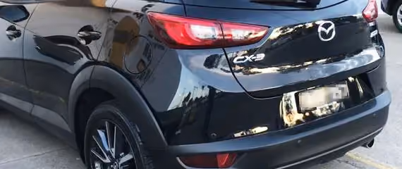Repaired back view of a black Mazda.