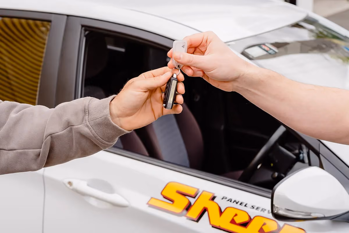 A Sheen team member handing the keys to a replacement vehicle over to a driver.