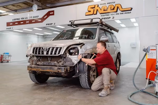 Photo inside Sheen's workshop showing technicians and cars in repair.