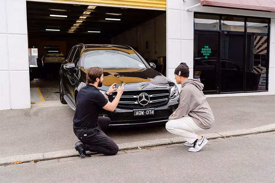 Sheen worker and customer taking photos of what needs repairing on a vehicle.