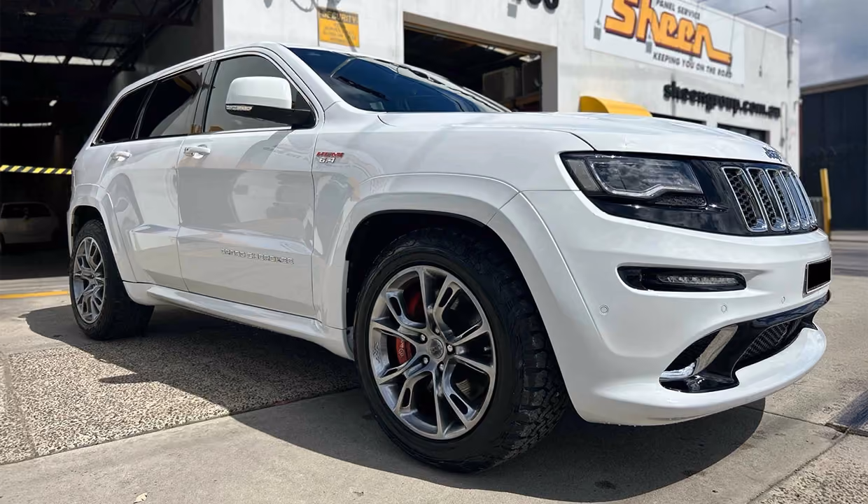 Displays a Jeep Grand Cherokee after full repair, restored to pristine condition with a new bumper, clean body panels, and a polished, factory-finish look.