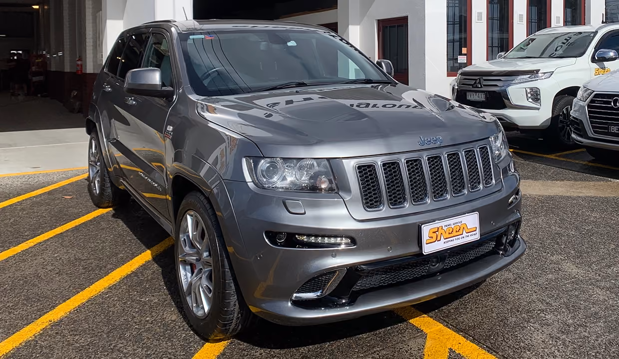 Displays a Jeep Cherokee after repair, featuring a perfectly restored front end with flawless paintwork, aligned body panels, and a polished finish.
