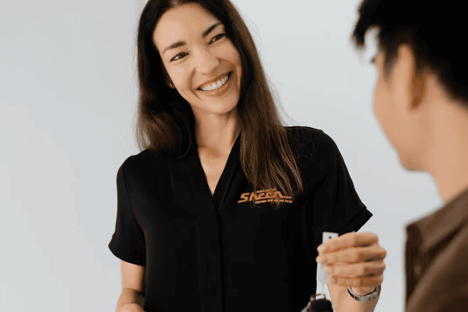 One of our insurance specialists laughing and chatting with a client, as she hands over the keys to an accident replacement vehicle while the client’s car gets repaired.