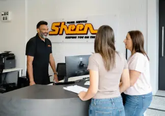 Customer discussing car insurance excess and not-at-fault accident repairs with Sheen panel service staff at the reception desk.